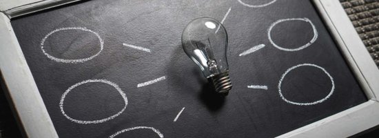 Chalkboard with a lightbulb on it surrounded by thought bubbles