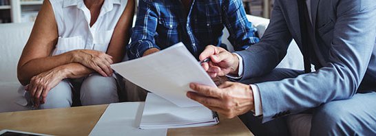 A man in a suit is showing a document to an older couple