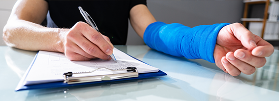 Person in cast writing on clipboard
