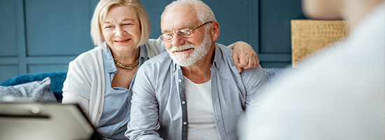 Two older people smiling and sitting across from someone